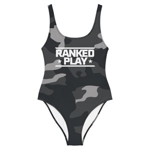 May include: A black and gray camouflage print one-piece swimsuit with the text "RANKED PLAY" in white.