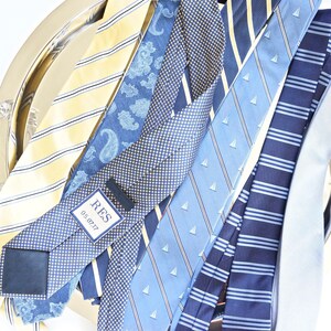 May include: A collection of blue and yellow patterned neckties on a silver tray. One tie has a white tag with the text "RES 05.07.17".
