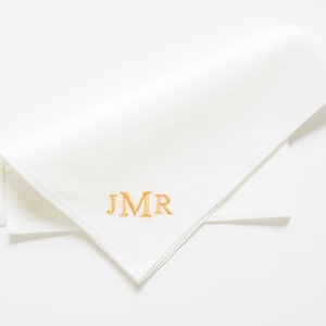 May include: White linen handkerchief with gold embroidered initials "JMR"