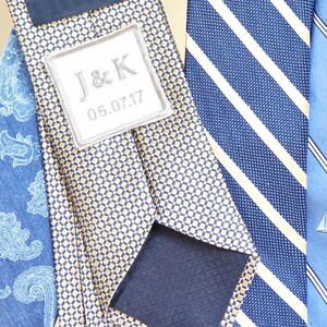 May include: Three neckties, one with a gold and navy pattern, one with a white and navy striped pattern, and one with a blue and white sailboat pattern. The gold and navy tie has a white label with the text "J&K 05.07.17".