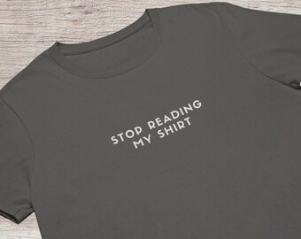 May include: A dark gray t-shirt with the text "STOP READING MY SHIRT" printed in white on the front.