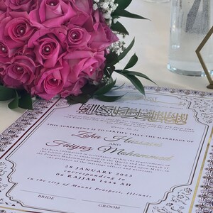 May include: A white wedding certificate with gold and burgundy accents. The certificate states "This agreement is to certify that the marriage of Lopa Husain and Faiyaz Mohammed has been solemnised in accordance within the requirements of the Islamic Law, as enshrined in the Quran and the Sunnah of the Prophet Muhammad (pbuh), with the agreed upon Mahr, in the presence of the marriage officer and witnesses. 28 January 2023 corresponding to 06 Rajjab 1444 AH in the city of Mount Prospect, Illinois."