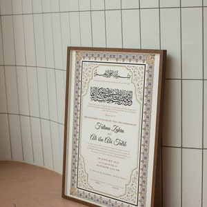 May include: A framed Islamic marriage certificate with ornate gold and white calligraphy. The text reads "This agreement is to certify that the marriage of Fatima Zahra and Ali ibn Abi Talib." The date is 28 January 2023, corresponding to 06 Rajab 1444 AH. The city of marriage is in the city of Anywhere, United States.