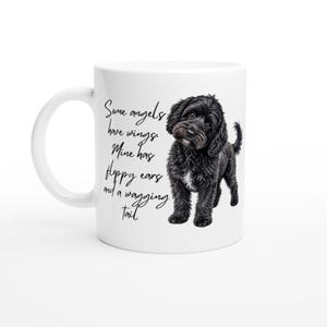 Peut inclure: Un mug en céramique blanche orné d'une illustration de chien noir aux poils bouclés et du texte cursif noir : Some angels have wings. Mine has floppy ears and a wagging tail. Le mug présente une anse incurvée et un corps cylindrique lisse.