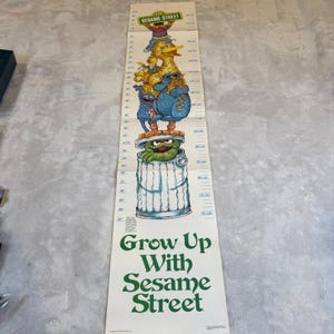 Könnte beinhalten: Ein Vintage-Höhenmesser von Sesame Street mit Charakteren wie Big Bird und Oscar the Grouch. Die Maße sind in Zoll und Zentimetern angegeben, mit dem Text "Grow Up With Sesame Street" in Grün.