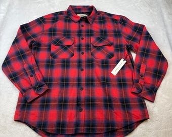 Op de afbeelding: Een rood, zwart en blauw geruit flanellen overhemd met twee borstzakken en een knoopsluiting. Het shirt met lange mouwen heeft een kraag en manchetten met knopen. Een wit label met zwarte tekst hangt aan het shirt.