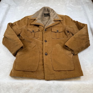 Könnte beinhalten: Braune Cordjacke mit beigem Kunstfellkragen und -futter. Die Jacke hat vier Vordertaschen, Knopfverschlüsse und ein Etikett am Kragen. Vintage-Stil.