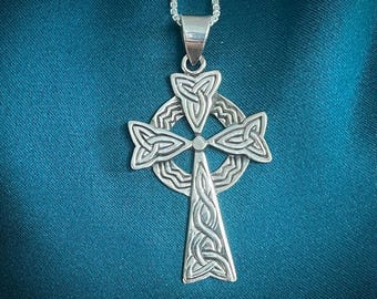 May include: A silver Celtic cross pendant with intricate knotwork designs. The cross is suspended from a silver chain.