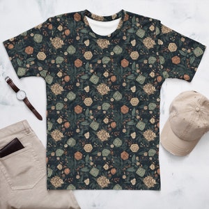 May include: A dark blue t-shirt featuring a repeating pattern of dice and floral designs. The dice are green and white, and the flowers are orange, brown, and green.