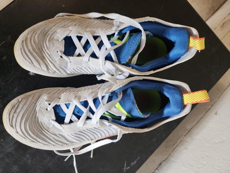 Puede incluir: Un par de zapatillas deportivas blancas y grises con cordones blancos. Las zapatillas tienen un dise&ntilde;o texturizado en los laterales y detalles azules y amarillos en el interior. Adecuadas para correr u otras actividades deportivas.