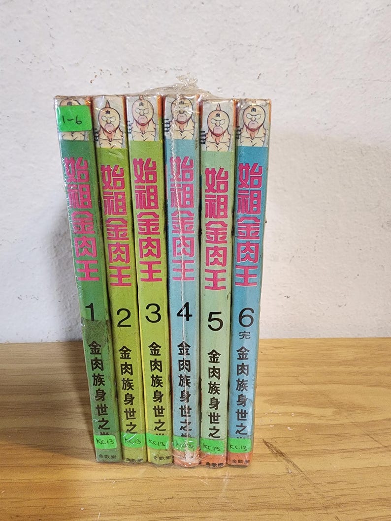 May include: A collection of six manga books, volumes 1-6, bound together. The spines are green, blue, and orange, with Japanese text and illustrations of a character's face. The books are wrapped in clear plastic and sit on a light wooden surface.