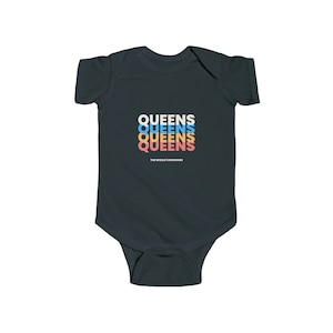 May include: A dark gray baby onesie with the text "QUEENS" repeated three times in different colors. The text "THE WORLD'S BOROUGH" is printed below the repeated text.