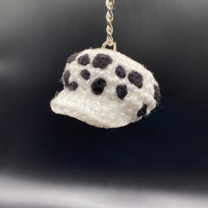 May include: White crocheted hat with black polka dots, attached to a silver keychain.