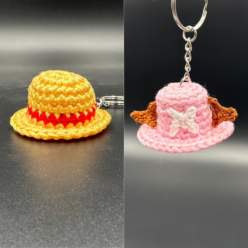 May include: Two crocheted hats, one yellow with a red band and one pink with a white X, are shown. The pink hat is attached to a silver key chain.