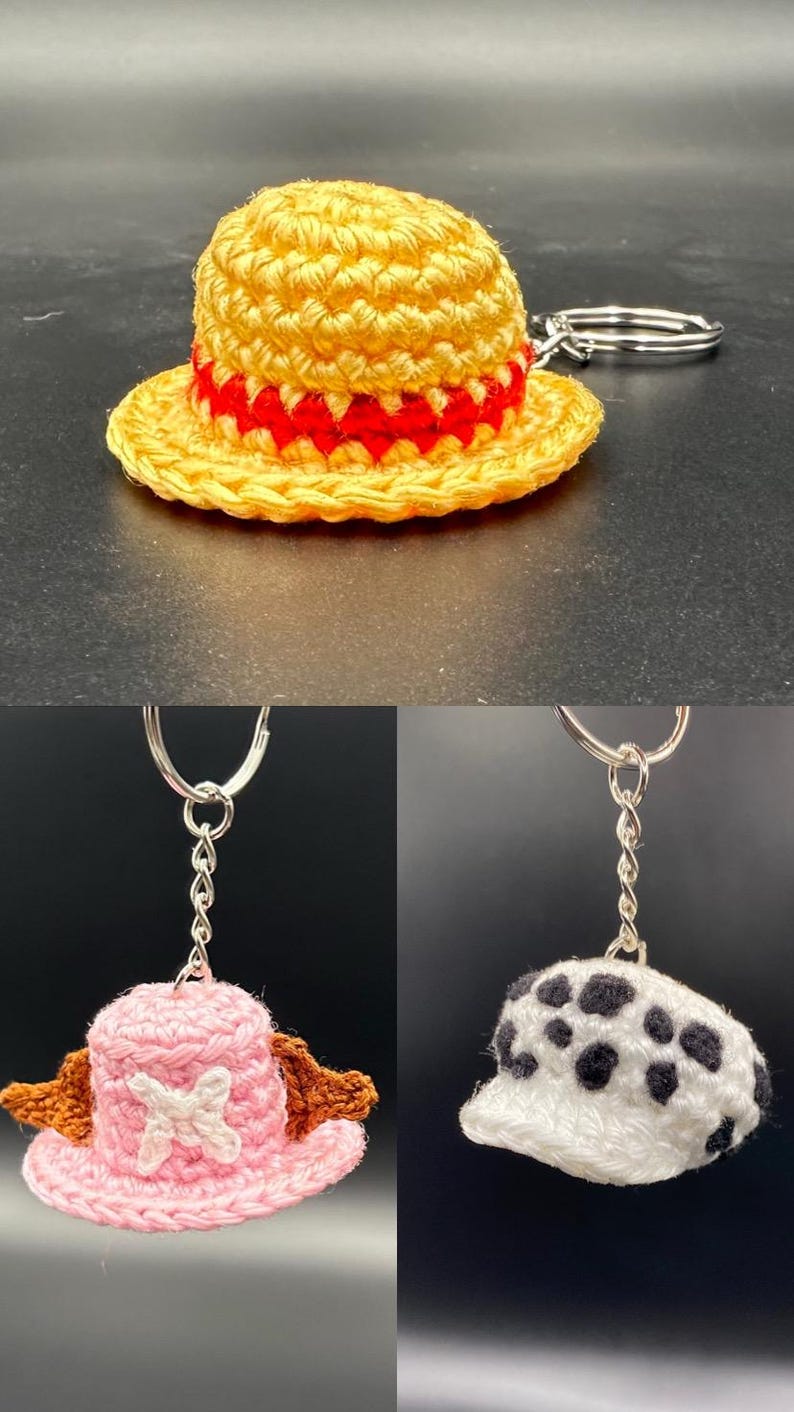 May include: Three crocheted hats with keychains. The first hat is yellow with a red band, the second is pink with brown accents and a white cross, and the third is white with black spots.