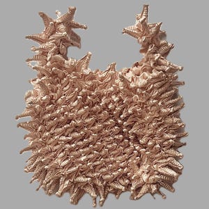 May include: A blush pink, ruffled, fabric handbag with a unique, spiky, textured design.