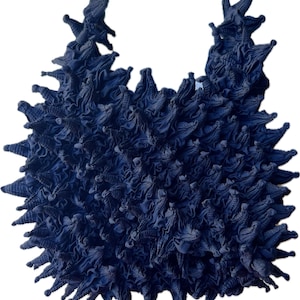 May include: A dark blue fabric sculpture with a unique, spiky texture. The fabric is gathered and twisted to create a three-dimensional form.