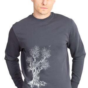 May include: A dark grey sweatshirt with a white outline of a tree on the left side of the chest. The tree has a bird flying above it.