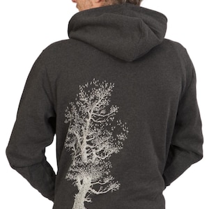 the back of a person wearing a grey hooded sweatshirt with a white tree design on the back.