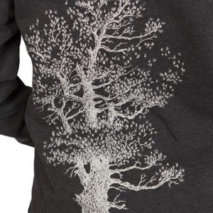 a close-up view of a person wearing a grey sweatshirt with a white tree design on the back.