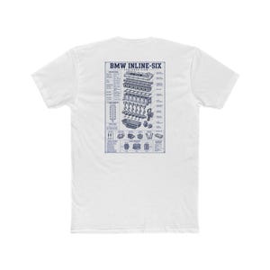 May include: A white short-sleeve t-shirt featuring a dark blue graphic on the back. The print displays an exploded view diagram of a BMW inline-six engine with technical labels, specifications, and the text BMW INLINE-SIX EXPLODED VIEW.
