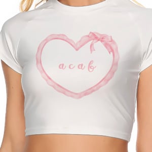 以下が含まれることがあります： ピンクの水彩画のハートのデザインとハートの中に「a c a b」という文字が入った白いクロップトップ