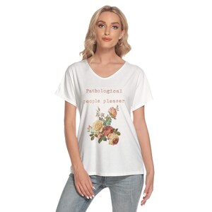 May include: White scoop-neck t-shirt with the text "Pathological people pleaser" in a brown font. A floral bouquet in shades of pink, yellow, and green is printed below the text. The shirt is worn by a person.