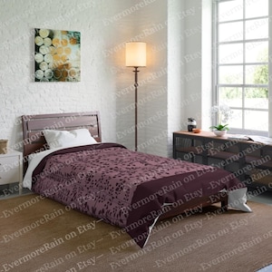 May include: A single bed with a dark brown headboard and a purple and white patterned duvet cover. The bed is in a bedroom with a white brick wall, a floor lamp with a white lampshade, and a window with white blinds.