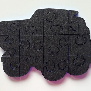 Może przedstawiać: Czarny element puzzli z pianki w kształcie samochodu z niebieskimi krawędziami. Puzzle składa się z 12 element&oacute;w.
