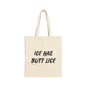 May include: Cream-colored tote bag with black text that reads "ICE HAS BUTT LICE." The bag has two handles and is made of a canvas-like material. The text is in a bold, handwritten style.