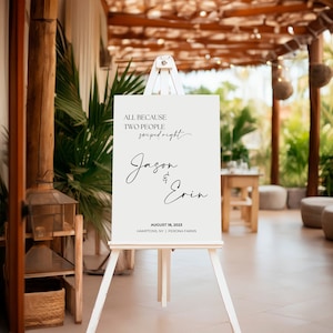May include: A white sign with black text announcing a wedding for Jason and Erin. The text reads "All because two people swiped right." The date and location are also included: "August 18, 2023, Hamptons, NY | Perona Farms."