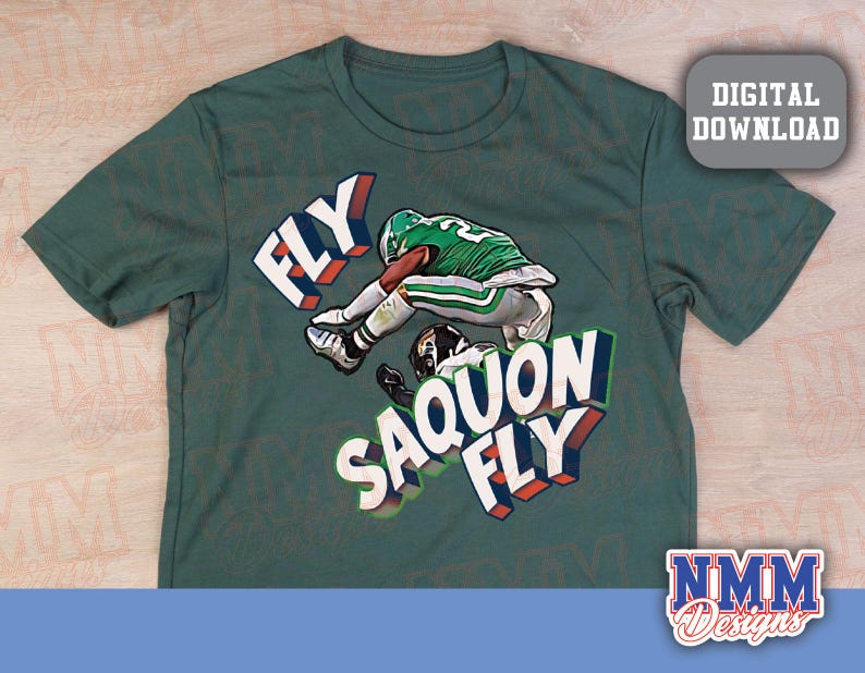 K&ouml;nnte beinhalten: Gr&uuml;nes T-Shirt mit einem Footballspieler in gr&uuml;n-wei&szlig;er Uniform und den Worten "FLY SAQUON FLY" in 3D-Design. Das Shirt hat auch eine "DIGITAL DOWNLOAD" Grafik und das "NMM Designs" Logo.