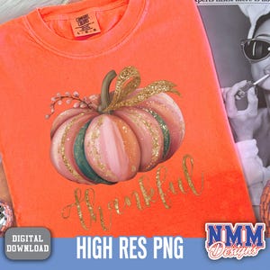 May include: Orange Comfort Colors t-shirt featuring a watercolour pumpkin design. The pumpkin is pink, green, and gold, with the word "thankful" in gold script. The shirt is a digital download.