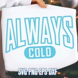 Może przedstawiać: Biały projekt graficzny z napisem "ALWAYS COLD" w jasnoniebieskim kolorze, z typami plików SVG, PNG, EPS i DXF na dole. Projekt jest trzymany przez osobę.