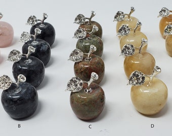 May include: Assortment of 5 different colored gemstone apple figurines. Each apple is carved from a different type of gemstone, including rose quartz, black obsidian, green aventurine, yellow jasper, and brown jasper. Each apple has a silver leaf and stem.