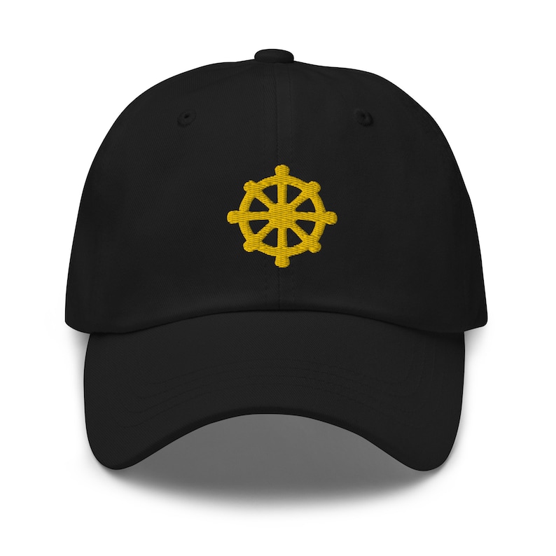 Puede incluir: Una gorra de b&eacute;isbol negra con un s&iacute;mbolo Dharmachakra bordado en oro.