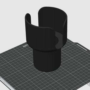Op de afbeelding: Een zwarte, 3D-geprinte bekerhouder met een cilindrische basis en een gebogen bovenkant. De houder is ontworpen om een beker of fles stevig vast te houden. Het object staat op een grijs rasteroppervlak.