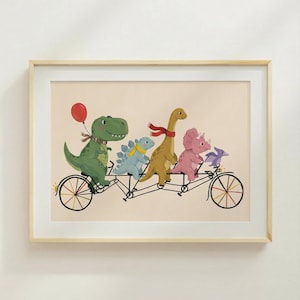 May include: A framed print showing a tandem bicycle ridden by five dinosaurs in a playful illustration. The dinosaurs are depicted in green, blue, yellow, and pink, with a red balloon and scarves. The background is a light beige colour.