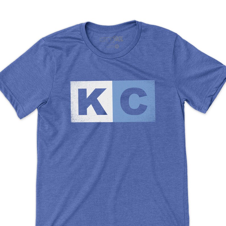 May include: A blue t-shirt with a white and blue "KC" graphic printed on the front.