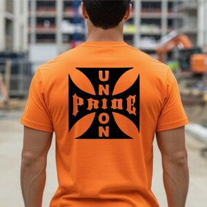 May include: A bright orange short-sleeved t-shirt featuring a large black iron cross graphic on the back. The graphic contains the text UNION PRIDE arranged vertically and horizontally within the cross shape in a bold, dark font style.