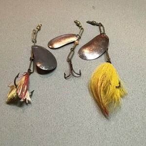 Old scarce fishing tackle. Vintage spinning lures. Kidney shaped blades with red backs, two hair skirted. A nice collectible display.