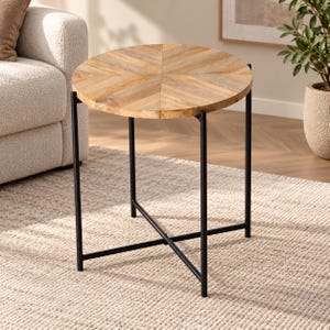 May include: A round side table featuring a light brown wooden top with a chevron pattern. The table is supported by a black metal frame consisting of four straight legs connected by a cross-brace structure at the base for stability and support.