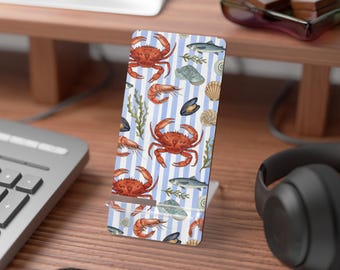 Könnte beinhalten: Ein weißer Telefonständer mit blau-weißem Streifenmuster mit Illustrationen von Krabben, Garnelen, Fischen, Muscheln und Seetang. Der Ständer ist aus einem haltbaren Material gefertigt und für ein Telefon konzipiert.