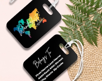 Puede incluir: Dos etiquetas de equipaje negras con cordones blancos. Una etiqueta presenta un mapa del mundo colorido y la palabra "Wanderlust" en escritura blanca. La otra etiqueta dice "Belongs To" y tiene espacio para el nombre y la dirección del propietario.