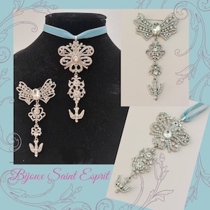 May include: Three silver and crystal brooches with a butterfly design. The brooches are on a blue ribbon and a white background. The text "Bijoux Saint Esprit" is at the bottom of the image.