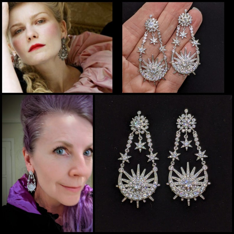 May include: A pair of silver earrings with a crescent moon and star design. The earrings are dangling and have multiple stars and a large star in the center.