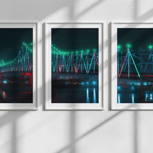 May include: Three framed photographs of a bridge illuminated at night with green and red lights. The bridge is reflected in the water below.