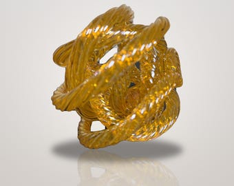 May include: A spherical sculpture crafted from translucent amber-colored glass, featuring a series of interconnected, twisted rope-like strands that create an intricate, open-work design with a reflective, glossy surface finish.