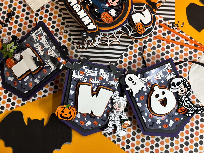 May include: Halloween-themed banner with Mickey Mouse characters. The banner features the numbers "one" and "two" with a black and orange polka dot background. The banner is decorated with bats, pumpkins, ghosts, and spiders.