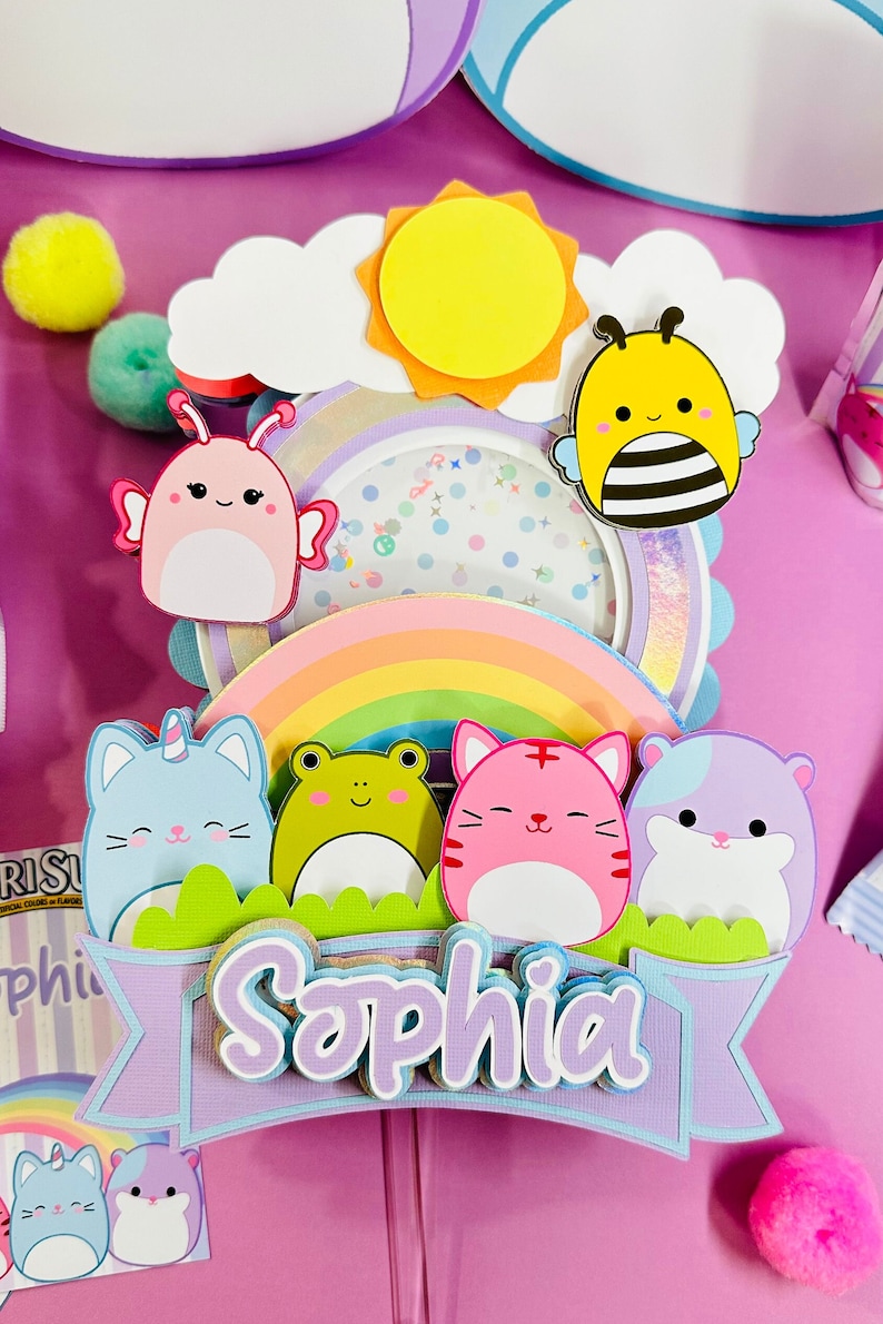 May include: A purple banner with the name 'Sophia' in white and purple letters. The banner is decorated with a rainbow, a cloud, a sun, a bee, a butterfly, a cat, a frog, and a hamster. The characters are all cartoon-like and have friendly faces.